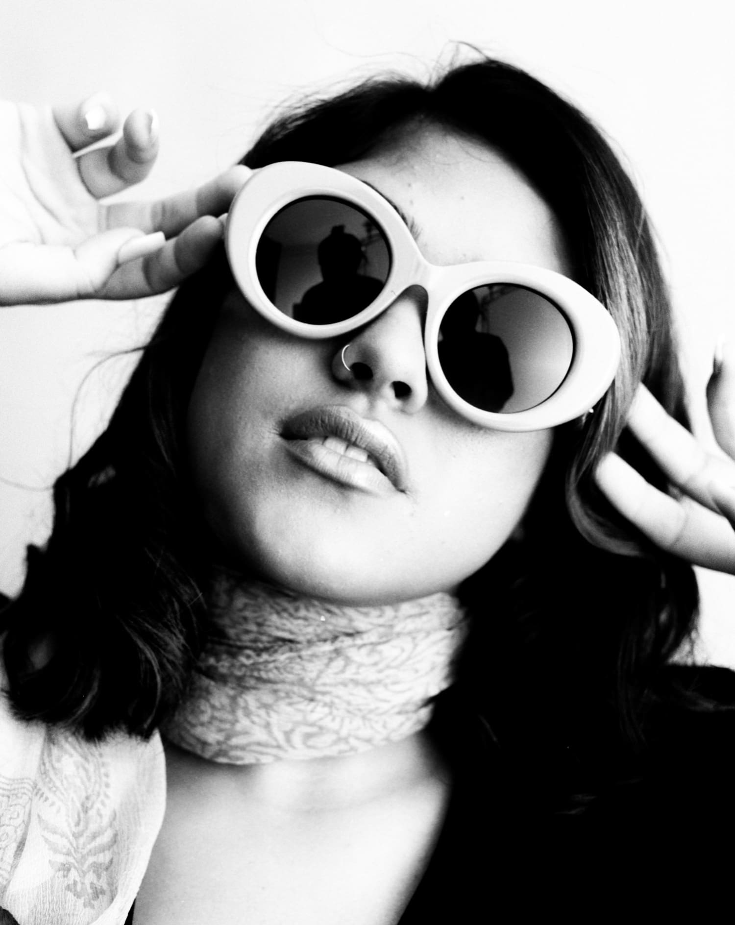 Black and white portrait of a woman in round white sunglasses and a lace choker