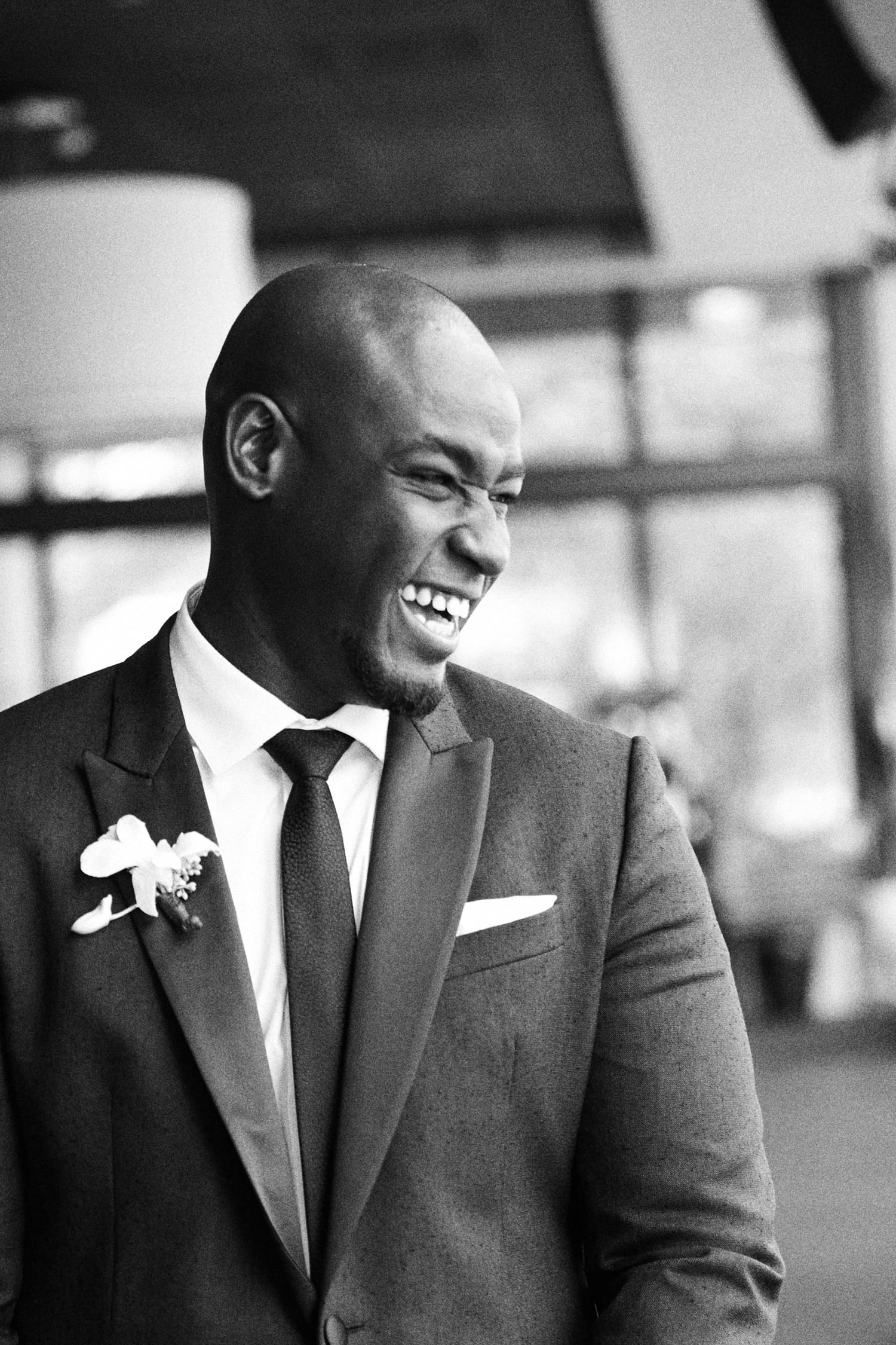 Black and white portrait of a laughing groom in a suit with a boutonniere, wedding in Miami