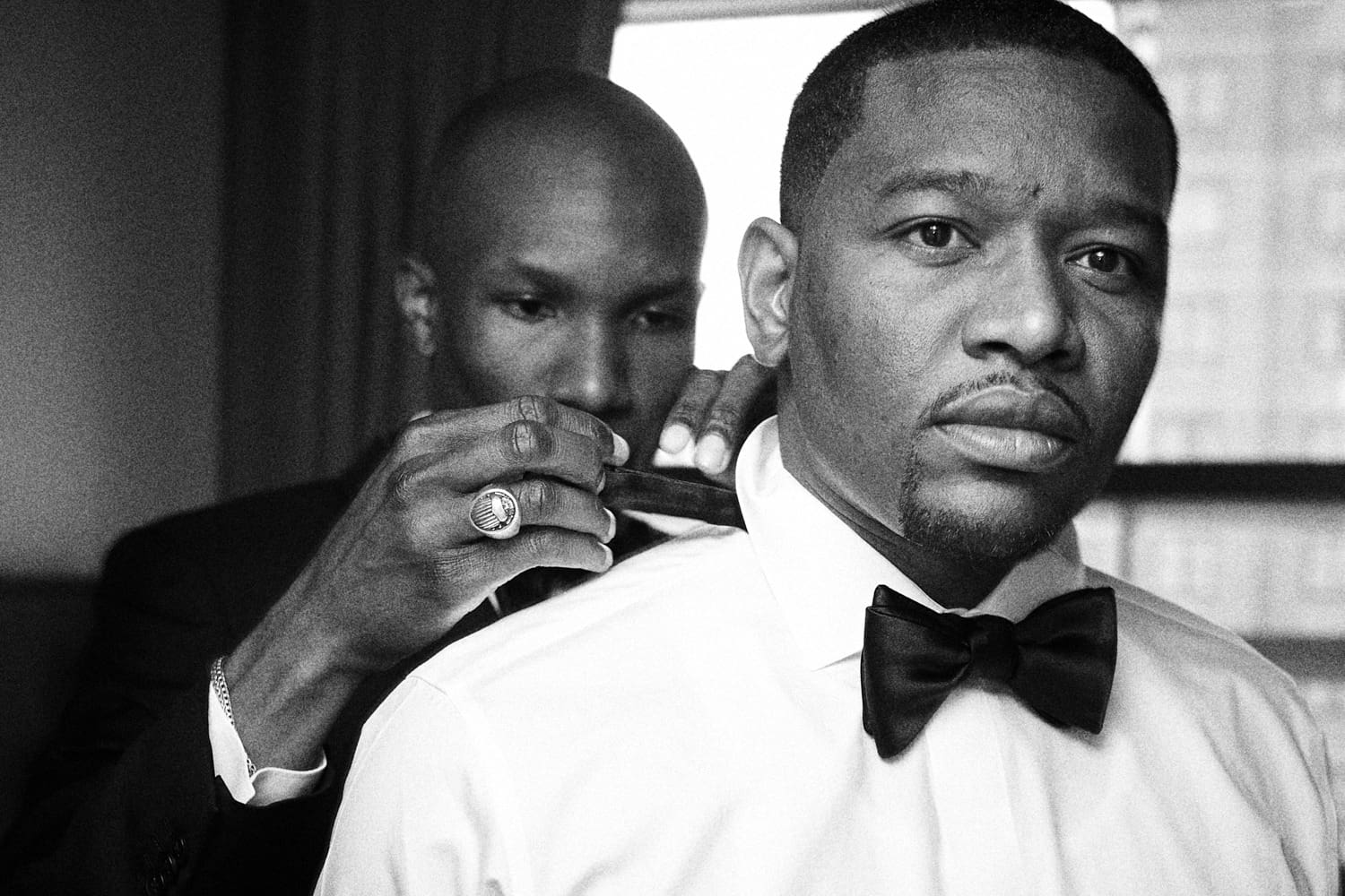 Black and white portrait of a groom in a bow tie having his collar adjusted, wedding in New York City