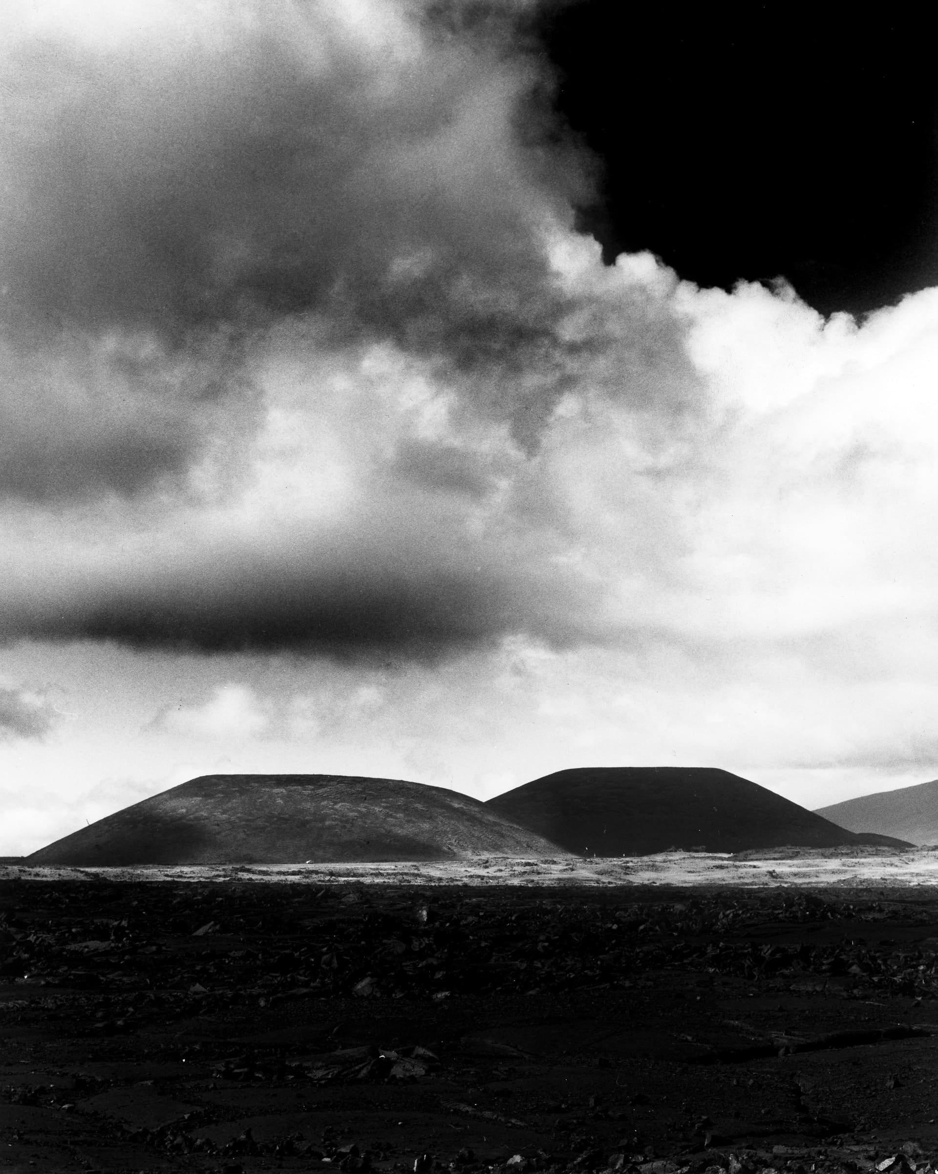 Black and white photograph of cinder cones and clouds along Saddle Road