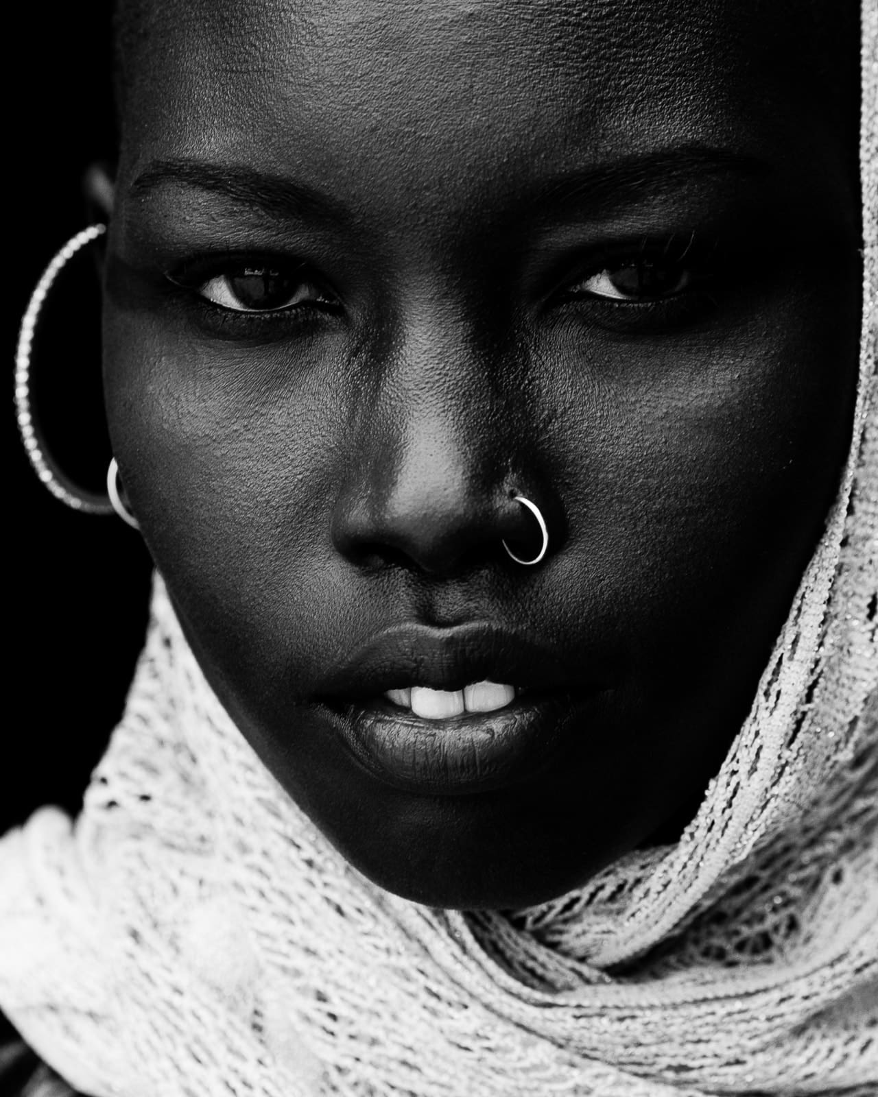 Close-up black and white portrait of a woman with hoop earrings and a lace head wrap