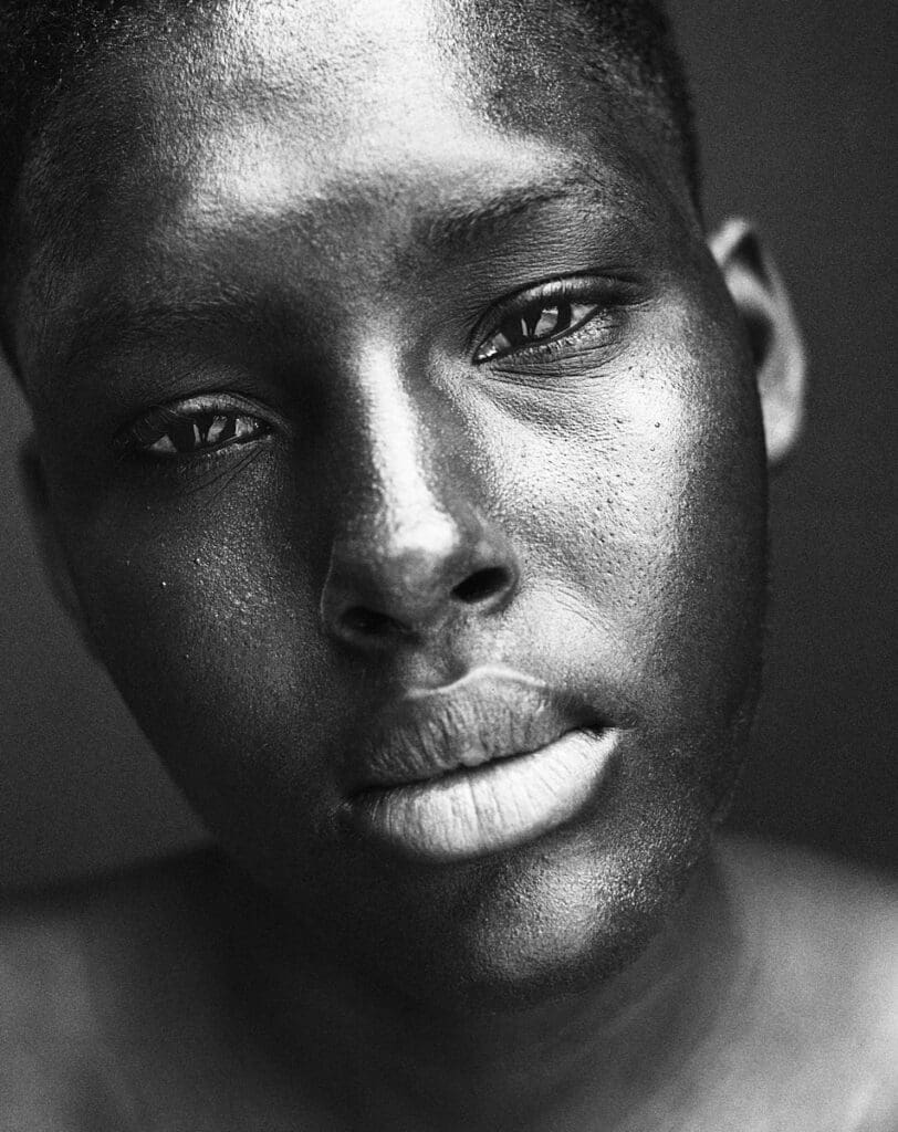 Close-up black and white portrait of a young man with dramatic light across his face