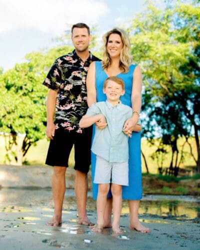 Family portrait on Kona beach at sunset by a photographer in Hawaii, featuring soft golden hour light and a beach backdrop.