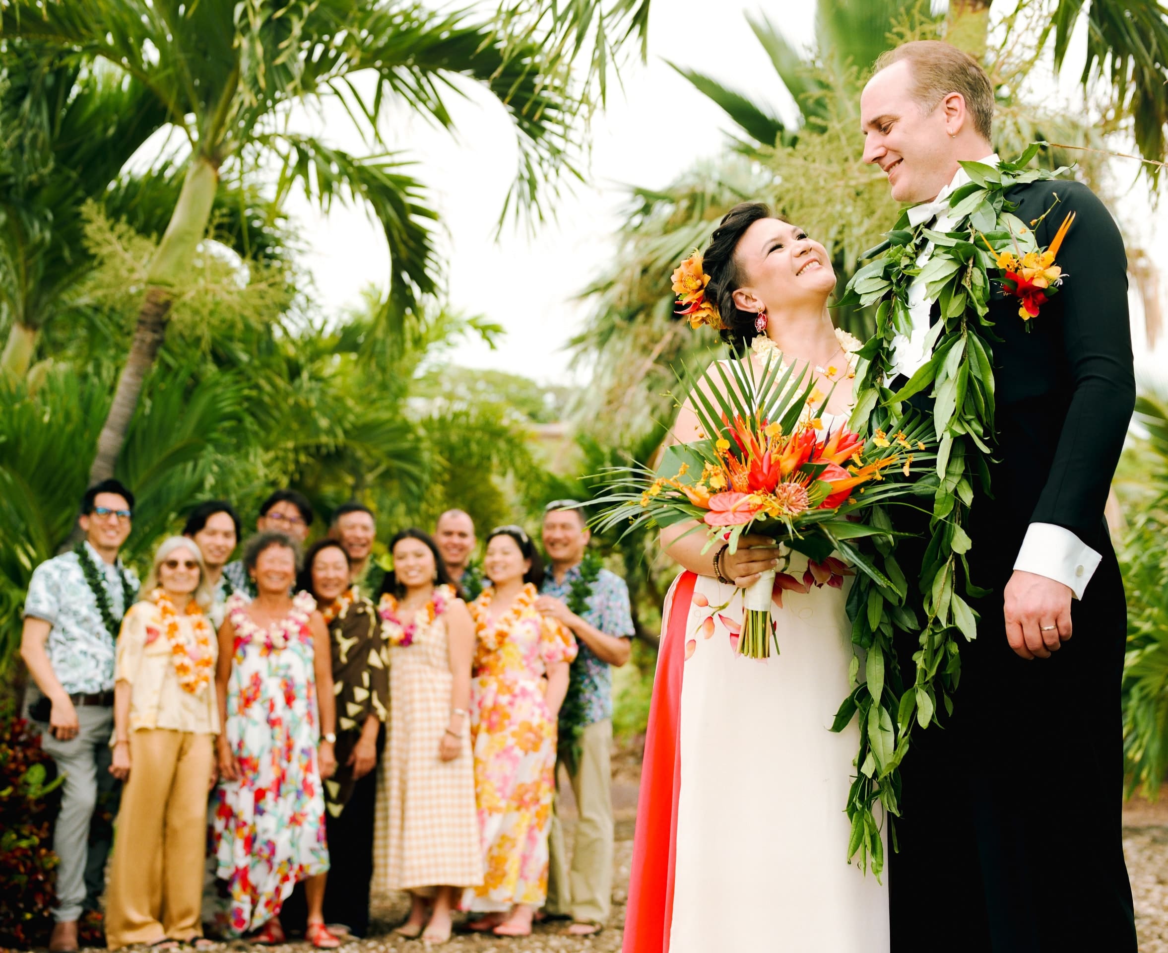 Bride and groom in leis with family and friends in a palm garden