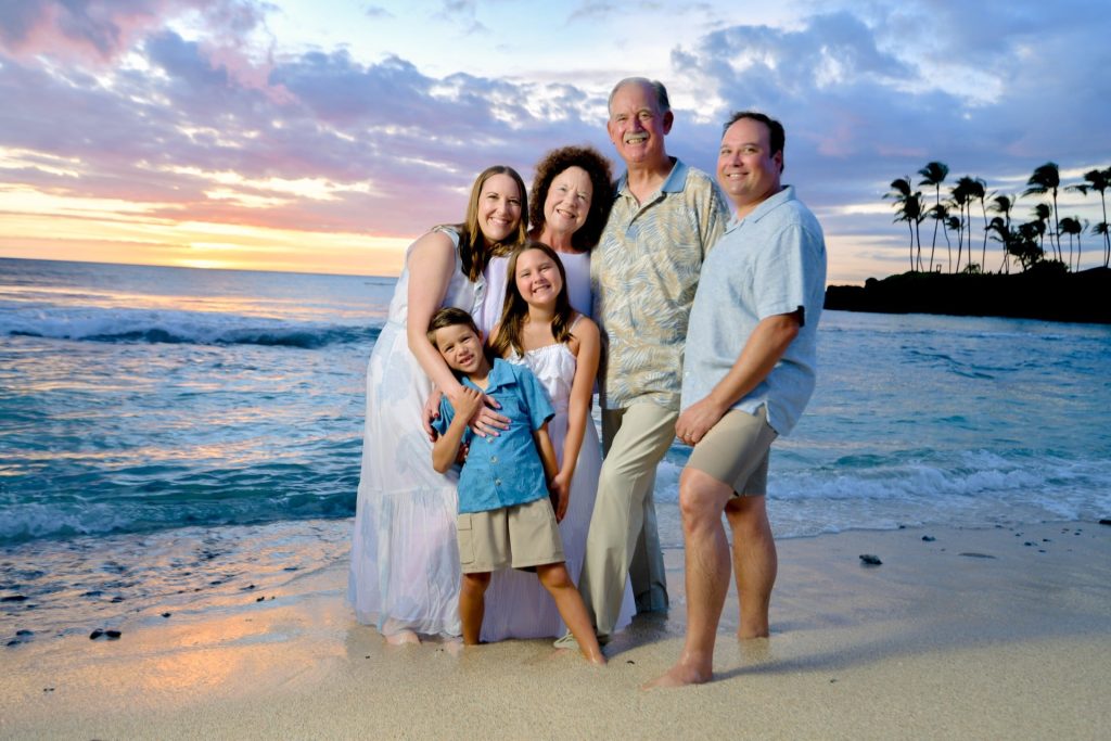 Extended family on the beach at sunset with palm trees behind them, flash sunset portrait on the Big Island of Hawaii