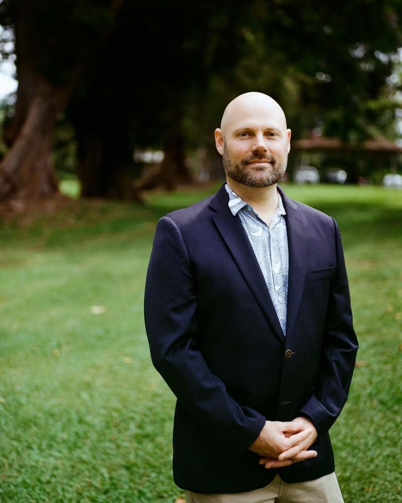 Man in a navy blazer standing on a lawn