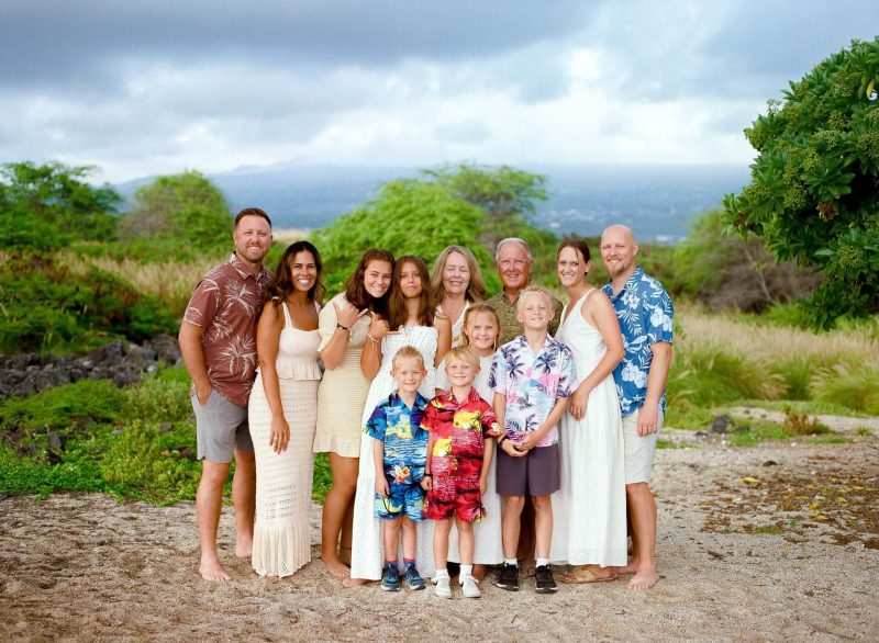 Extended family in coordinated outfits on a grassy bluff