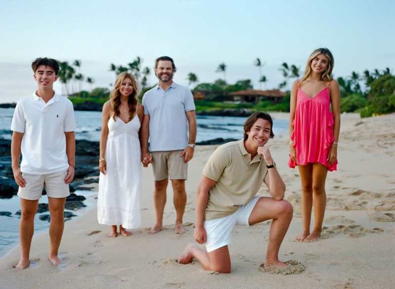 Family of five on a palm-lined beach at sunset