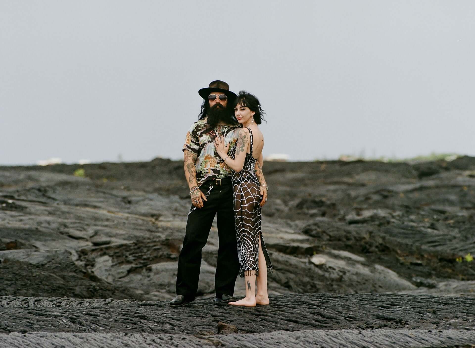 Couple standing on a black lava field under an overcast sky, photographer in Hilo Hawaii