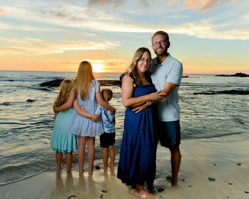 Family of five on the beach with the sun on the horizon, lit with flash, sunset family photographer in Kona Hawaii